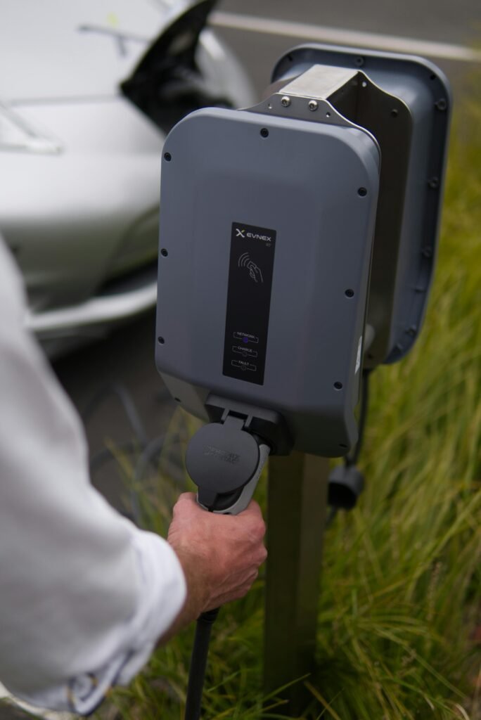 Close-up of a hand connecting an electric vehicle at a charging station in Christchurch, New Zealand.